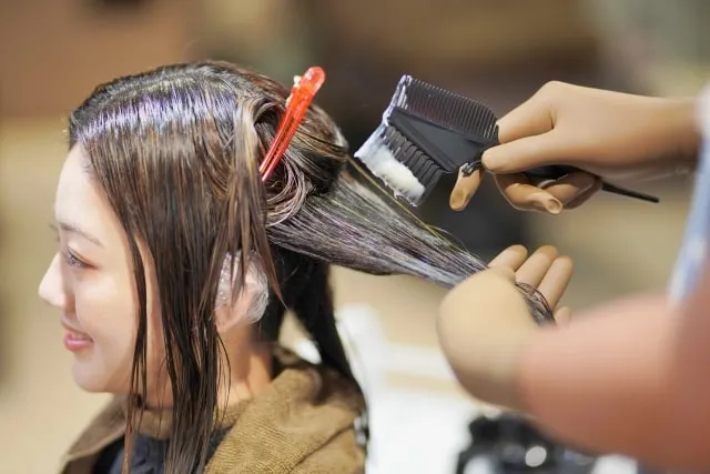ブラシでヘアカラーを塗布するスタイリスト