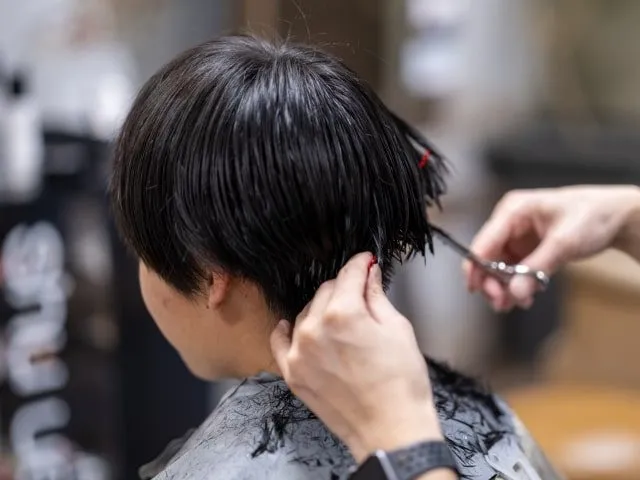 お客様の髪をはさみでカットするスタイリスト