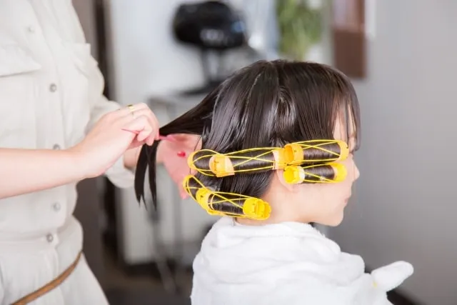 ヘアアイロンでお客様の髪をストレートにするスタイリスト